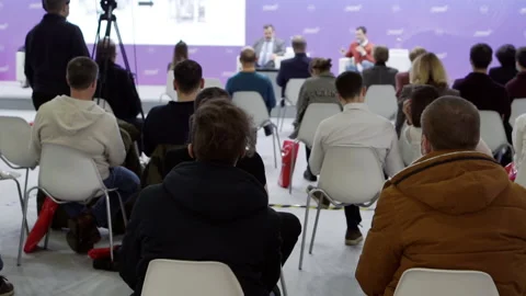 A video camera with a tripod captures the speakers in the conference room. Stock Footage 167668689