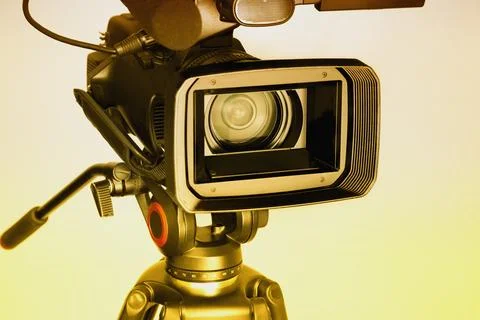 Video camera on a white background with a wide lens in warm light, profession Stock Photos