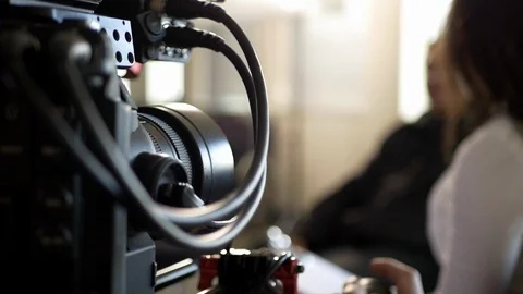 A video cameraman operates a camera with actors on a video production set. Stock Footage 99427783
