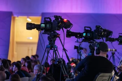 Video cameras and camera operators recording live conference event with tripods Stock Photos