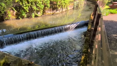 Video captures a landscaped mill stream flowing toward a small waterfall Stock Footage 336211881