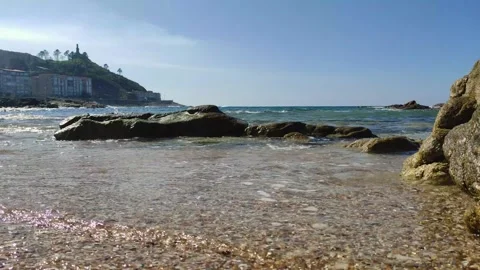 A video capturing waves washing over a seashell-covered shore in Baiona, Galicia Stock Footage 305153136