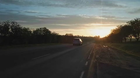 Video of a car going on a trip during a summer sunset on a long road Stock Footage 155753385