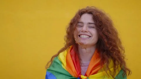 Video of cheerful non-binary person red hair with rainbow flag over shoulders Stock Footage 240617941