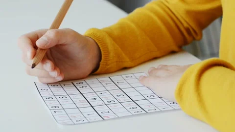 Video of close-up children's hands solving sudoku puzzle with a pencil as a h Stock Footage 133728522