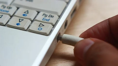 Video Close Up, Hand Plug and Unplug White audio Cable into Notebook Stock Footage 145439891