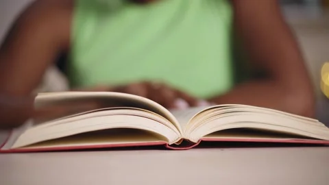 Video close up hands of young black woman at home reading a book. Selective Stock Footage 242808506