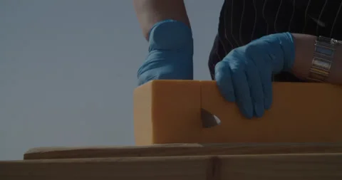A video of a close-up of a man cutting a block of cheese Stock Footage 239940641