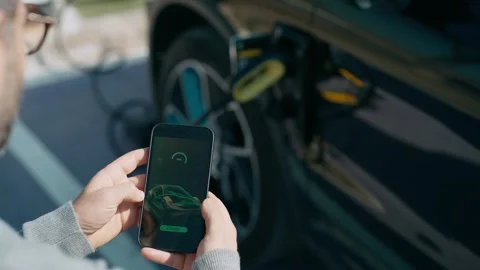 Video of close up of man using mobile phone while charging electro car at t.. Stock Footage 243176775