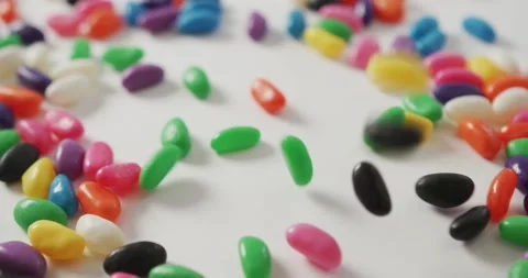 Video of close up of multi coloured sweets falling over white background Stock Footage 344324147