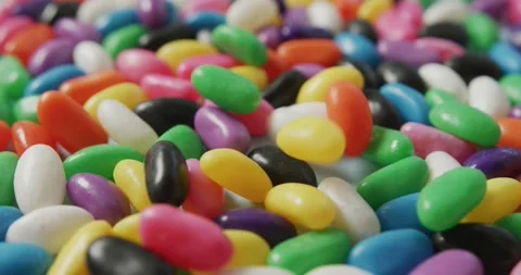 Video of close up of multi coloured sweets falling over blue background Stock Footage 344330233