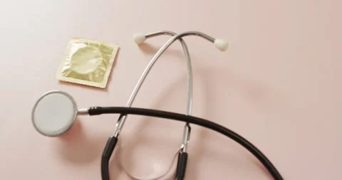Video of close up of stethoscope with condom on pink background Stock Footage 335807649