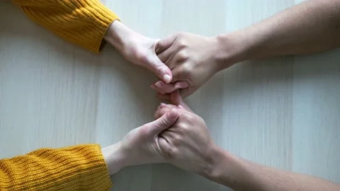 Video of close up of two cute friends holding hands on the table at home. Stock Footage 152816207