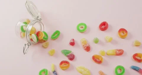 Video of colourful jelly candy and jar on pink background Stock Footage 337932064
