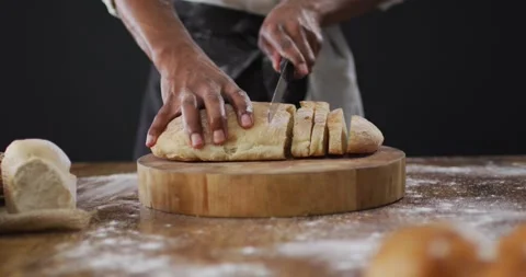 Video of cook cuts the loaf of bread on black background Stock Footage 336896622