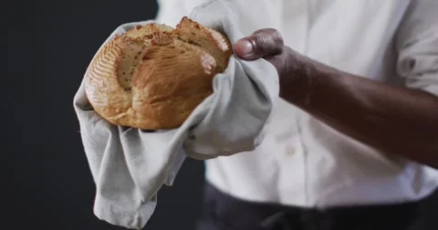 Video of cook holding loaf of bread on black background Stock Footage 337399317