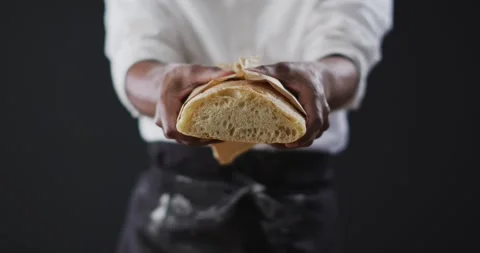 Video of cook holding loaf of bread on black background Stock Footage 340766255