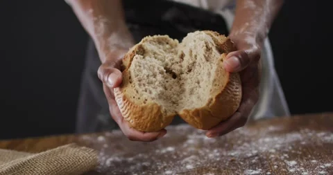 Video of cook holding loaf of bread on black background Stock Footage 340968116