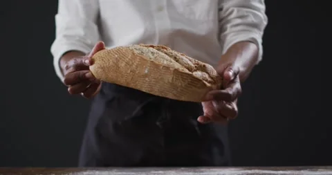 Video of cook holding loaf of bread on black background Stock Footage 342925814