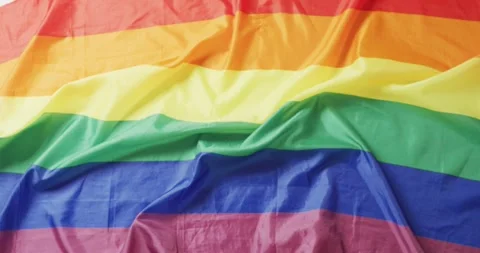 Video of creased rainbow flag lying on white background Stock Footage 340454030