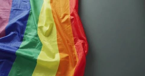 Video of creased rainbow flag lying on black background Stock Footage 346024822