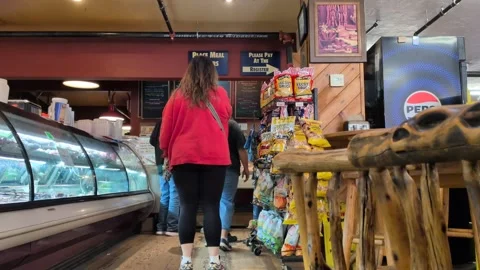 Video of customers lined up inside busy butcher shop with meat case Stock Footage 333715177