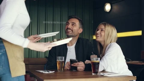 Video of cute couple using mobile phone while the waiter serves them potatoes Stock Footage 219605817