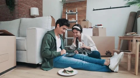 Video of cute couple using tablet while relaxing from moving in their new hou Stock Footage 221472502