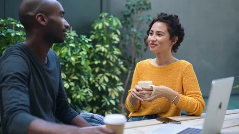 Video of a cute multiethnic couple drinking cup of coffee while talking in .. Stock Footage 237692019
