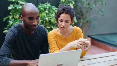 Video of a cute multiethnic couple using computer while talking in a garden.. Stock Footage 237692036