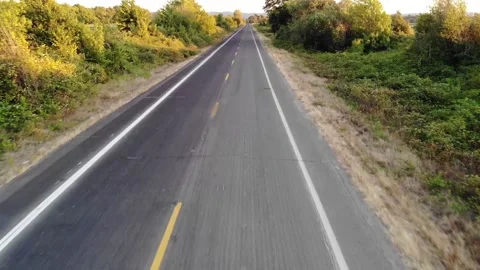 Video from a drone flying low over a deserted two lane road Stock Footage 157455570