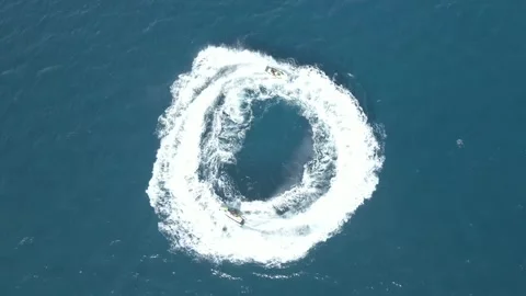 Video of a drone looking down while moving down towards a jet ski doing circles Stock Footage 245724582