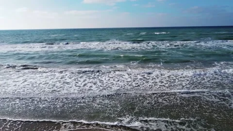 Video from a drone over beautiful waves against a blue sky with clouds. Slow Stock Footage 238894407