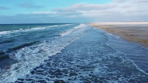 Video from a drone over a sandy beach with beautiful waves against a blue sk Stock Footage 238894380