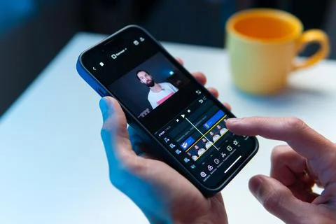 The video editor program on the phone. A young man is editing a video on his Stock Photos