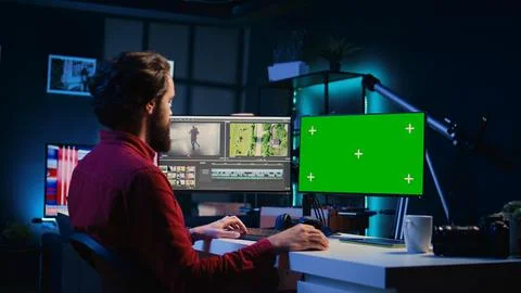 Video editor using editing software on green screen monitor to upgrade footage Fotos de archivo