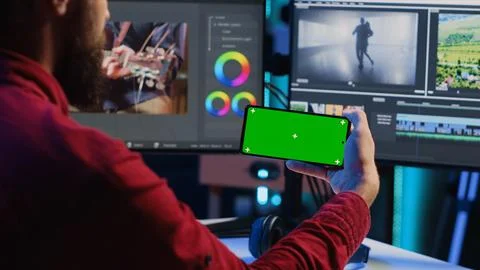 Video editor watching tutorial on mockup phone about editing color grading and Stock Photos