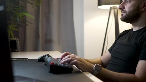 Video Editor Working at a Computer in a Studio. A bald man with a beard, si.. Stock-Footage 303012633