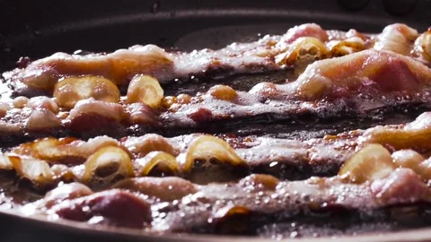 Video of egg being dropped on fried bacon Stock Footage 72415923