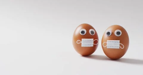 Video of eggs with eyes and face masks on a white surface Stock Footage 337623364