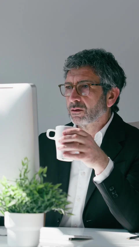 Video of elegant businessman drinking coffee while working on a computer in.. Stock Footage 340829355