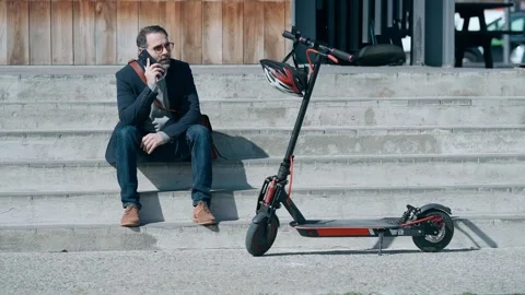 Video of elegant man using mobile phone while resting after riding an elect.. Stock Footage 243176793