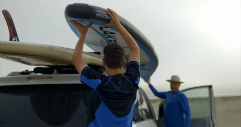 Video of father and son unloading paddleboards at beach. Vidéo 88377855