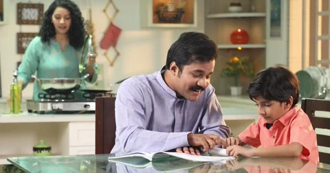 Video of father teaching lesson to his son while wife cooking in kitchen Stock Footage 255423433