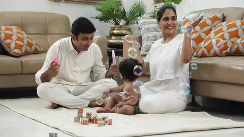 Video footage of an Indian dad blowing bubbles and his baby enjoying it. Stock Footage 229256053