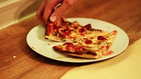 Video frame showing a hand picking up a slice of pizza, 2026 Stockbeeldmateriaal 330943593
