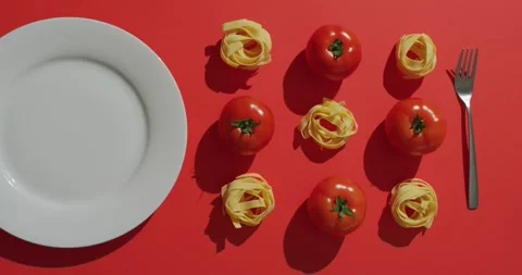 Video of fresh red tomatoes and pasta nests with plate and fork on red Vídeos de archivo 340766575