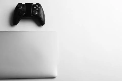 Video game controller and laptop on light background, top view with space for Stock Photos