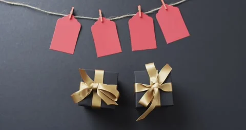 Video of gift tags on string, gift boxes with ribbons and copy space on black Stock Footage 331358727