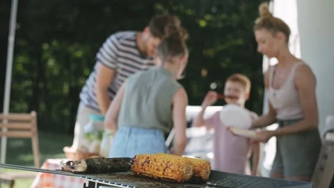 Video of grilled corn against the background of bustling family Stock-Footage 136090103